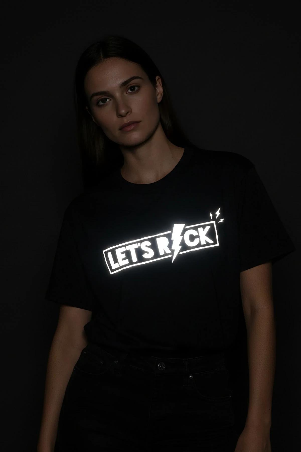 LET'S ROCK şimşek ikonlu reflektör baskılı siyah oversize tişört, ışık altında parlayan ön baskı, model üzerinde