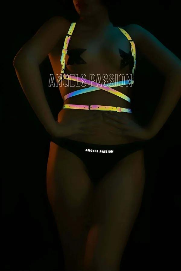 Rainbow reflective multi-strap body harness with holographic PU straps glowing gold pink and teal under dark lighting