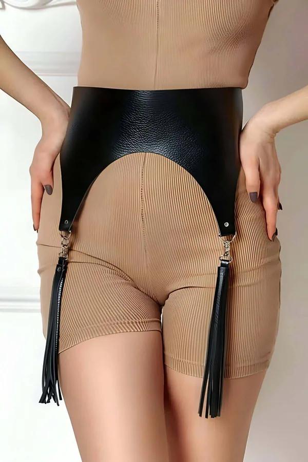 black faux leather wide waist harness with detachable tassels hanging at hips over beige ribbed shorts