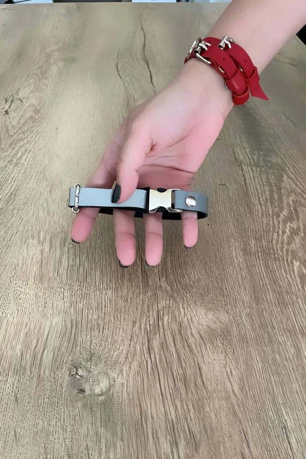 Grey vegan leather choker with silver quick-release snap buckle and side O-ring held in hand