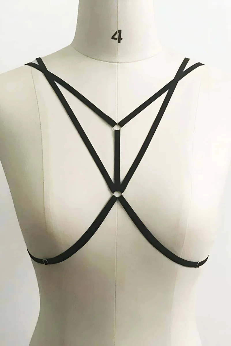 Black faux leather strappy harness close-up on chest with o-ring detail