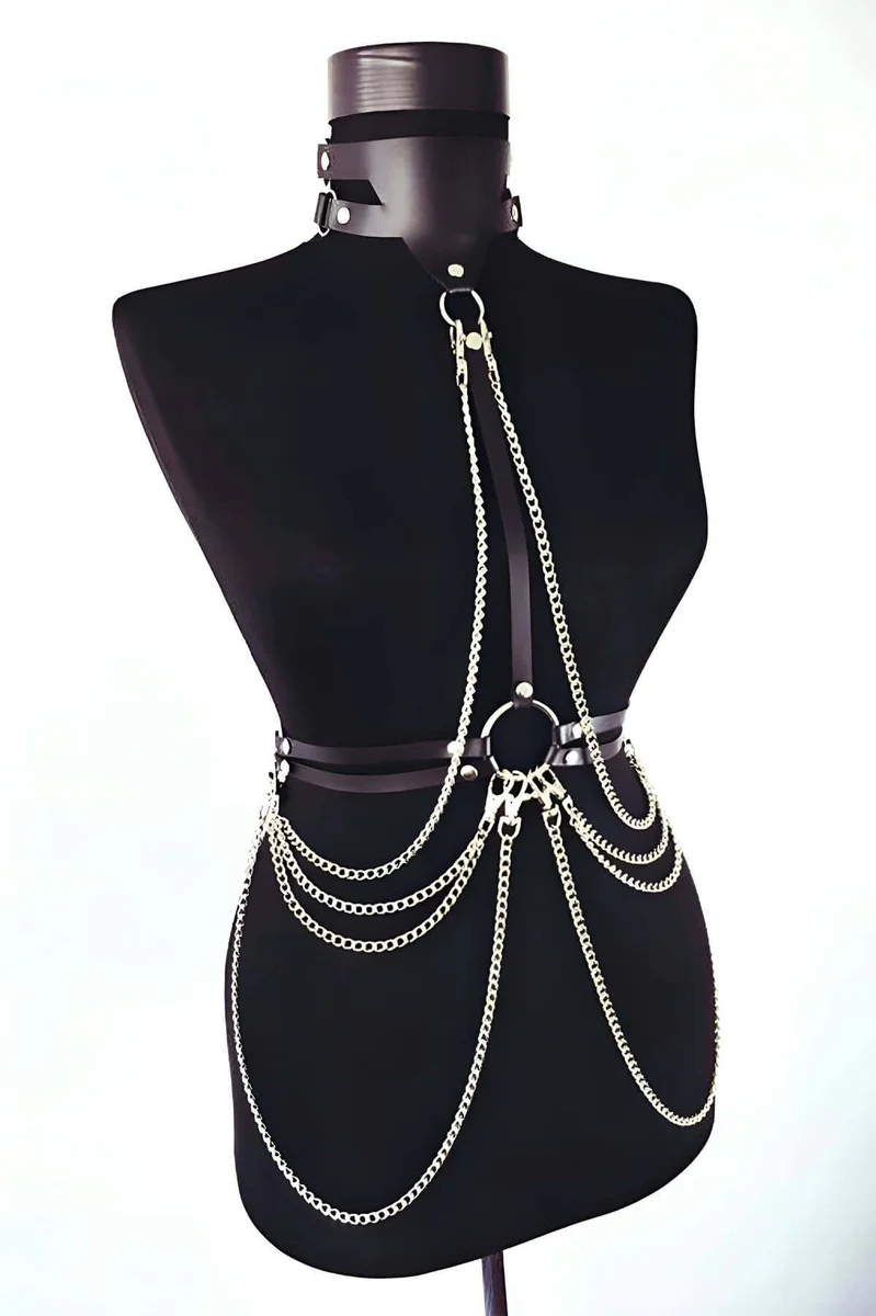 Close-up of black faux leather choker with O-ring detail and silver chain body harness.