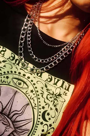 Silver multi-strand layered chain necklace with mixed links worn over black t-shirt