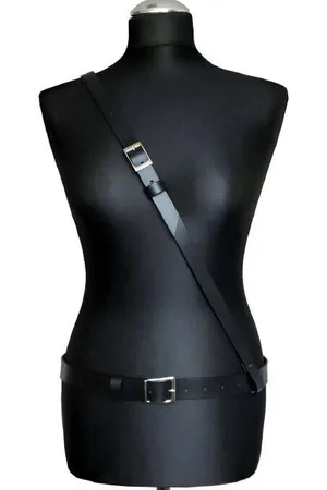 Minimalist black faux leather body harness with adjustable waist and shoulder straps and silver buckles.