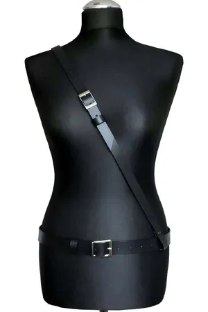 Minimalist black faux leather body harness with adjustable waist and shoulder straps and silver buckles.