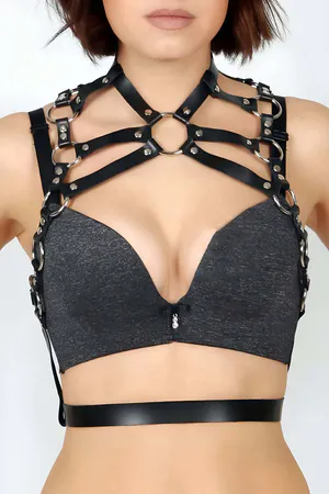 Black faux leather chest harness with multiple silver O-ring accents