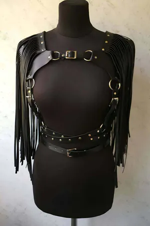 Black faux leather body harness with cascading fringe and studded belt.
