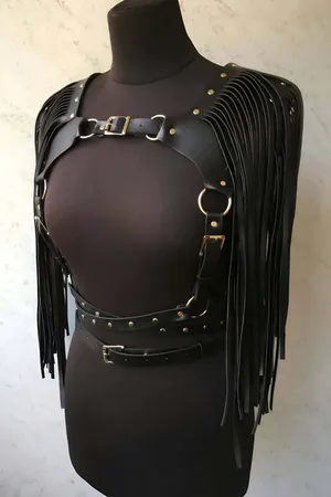 Black faux leather body harness with cascading fringe and studded belt.