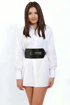 Black wide faux leather waist belt with silver buckle worn over a white shirt dress
