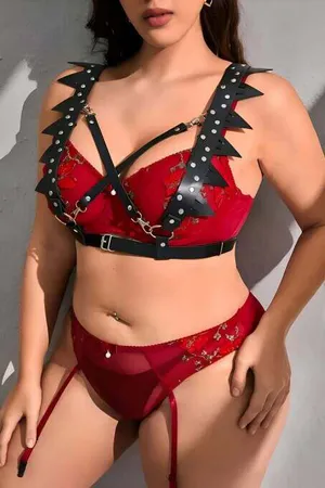Black faux leather spiked chest harness with silver hardware on a model