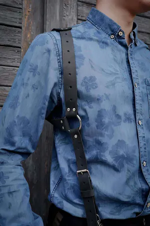 Black faux leather chest harness with adjustable straps and silver buckles on a person