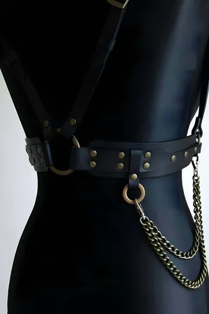 Black faux leather body harness with antique gold O-ring and decorative chain detail.