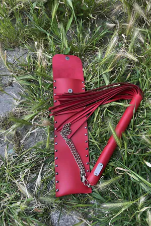Red Faux Leather Flogger with Riveted Storage Pouch on grass