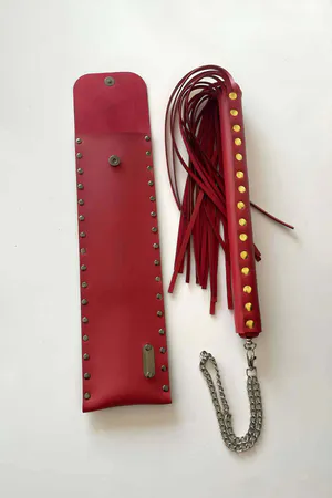Red Faux Leather Flogger with Riveted Storage Pouch on grass