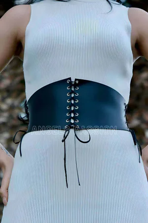 Black faux leather lace-up corset belt worn over a white dress