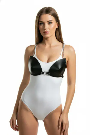 Black faux leather harness bra with O-ring and chain details, worn over a white bodysuit.