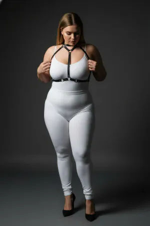 Black faux leather strappy body harness with silver O-rings and adjustable straps worn by a plus-size model.