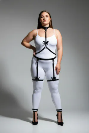 Black vegan leather body harness with choker, chest straps, O-rings, and decorative bow garter straps.